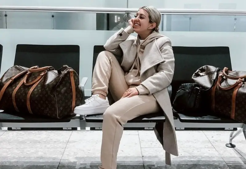 trendy woman on bench at airport